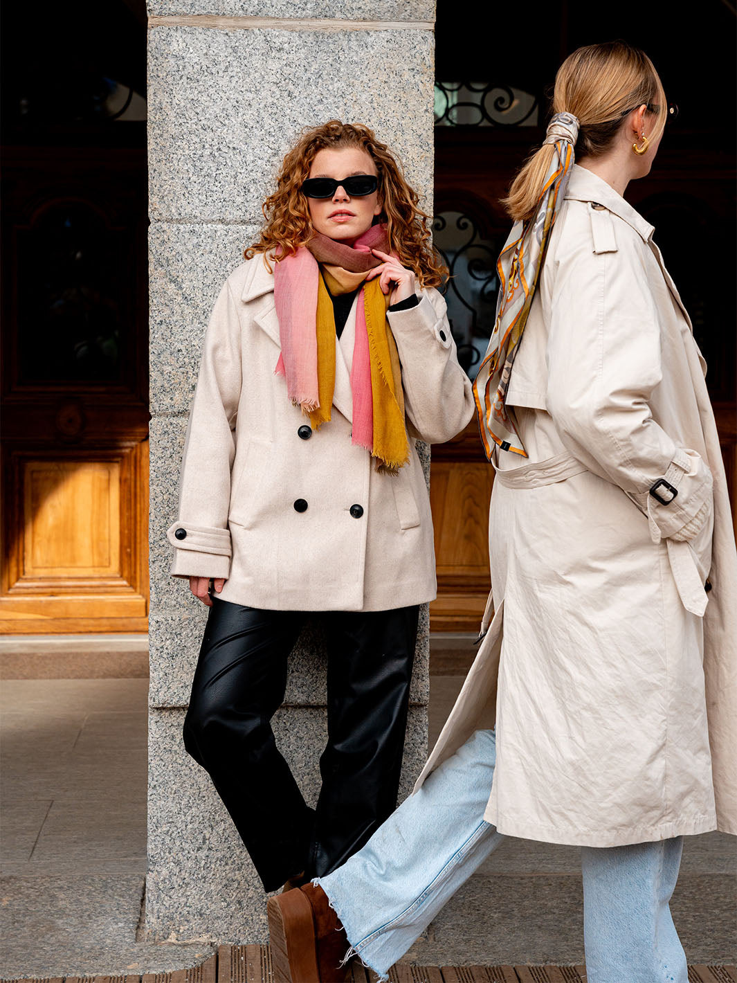 eine Frau sieht in die Kamera während eine andere Frau vorbeiläuft