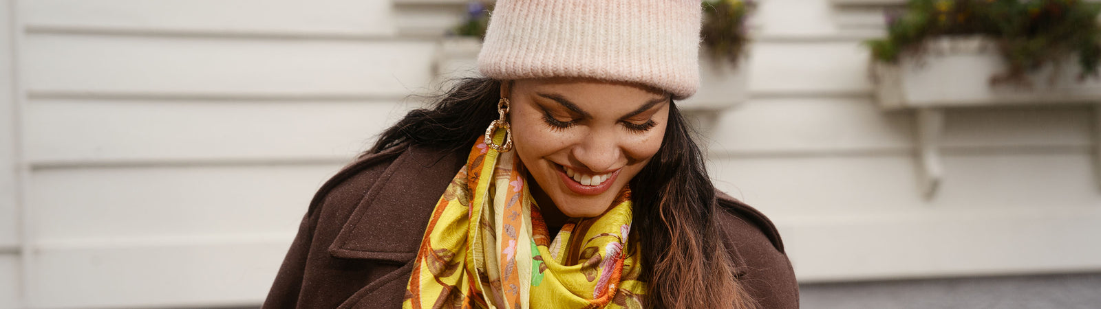 Nahaufnahme einer Frau mit gestrickter Wintermütze und bunt gemustertem Seidentuch am Hals