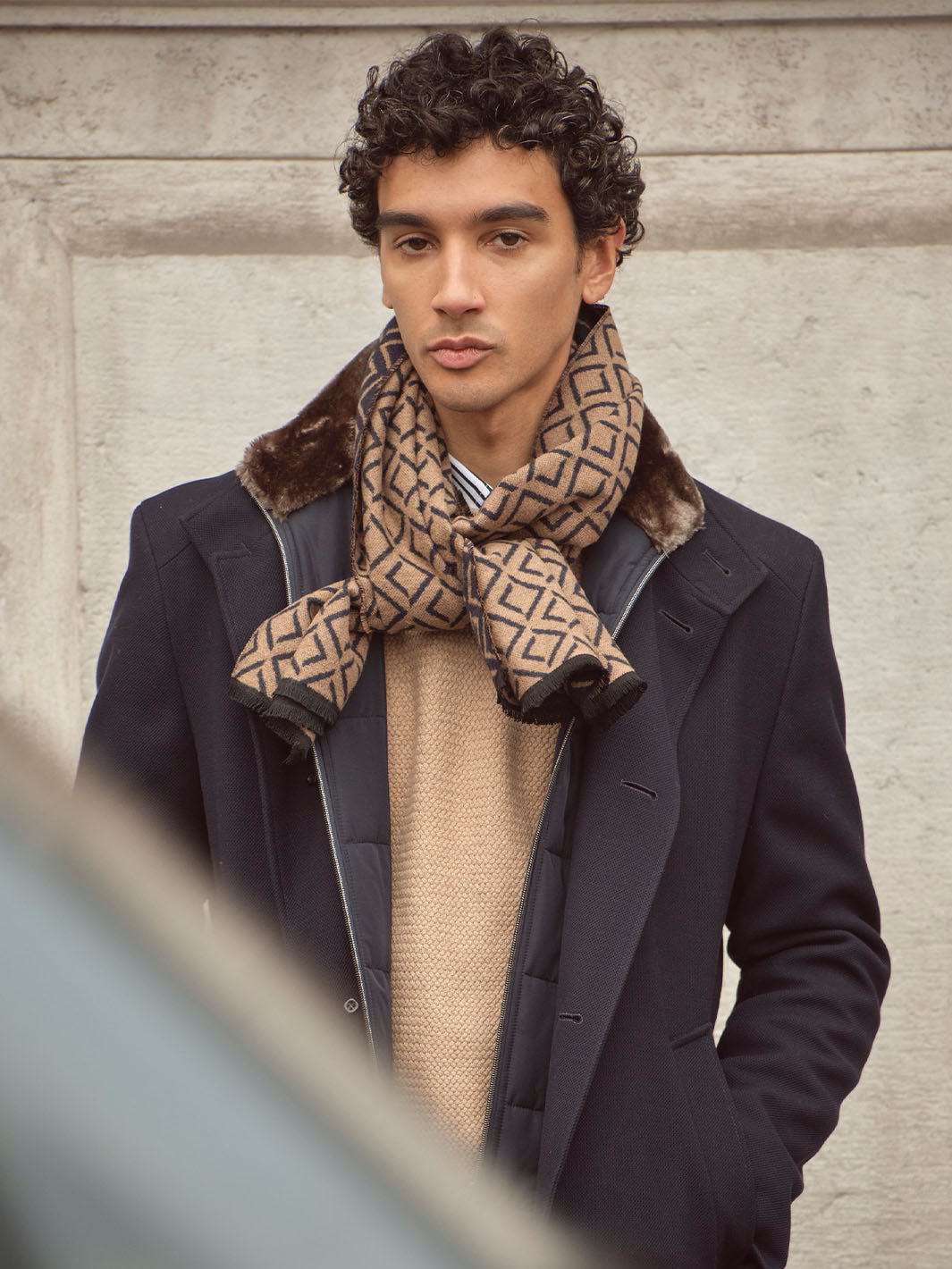 Mann mit Winterjacke und bugatti Schal 630328 hat die Hände in die Hosentaschen gesteckt und sieht in die Kamera