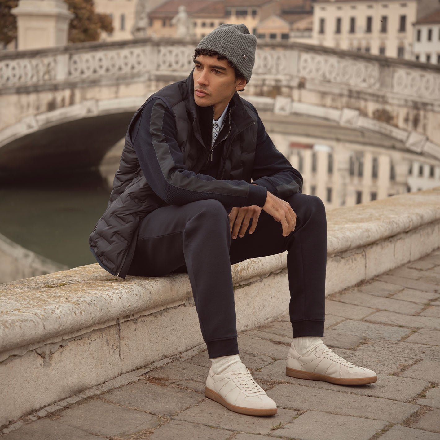 Mann in bugatti-Kleidung sitzt auf der Brüstung vor einem Kanal in Venedig