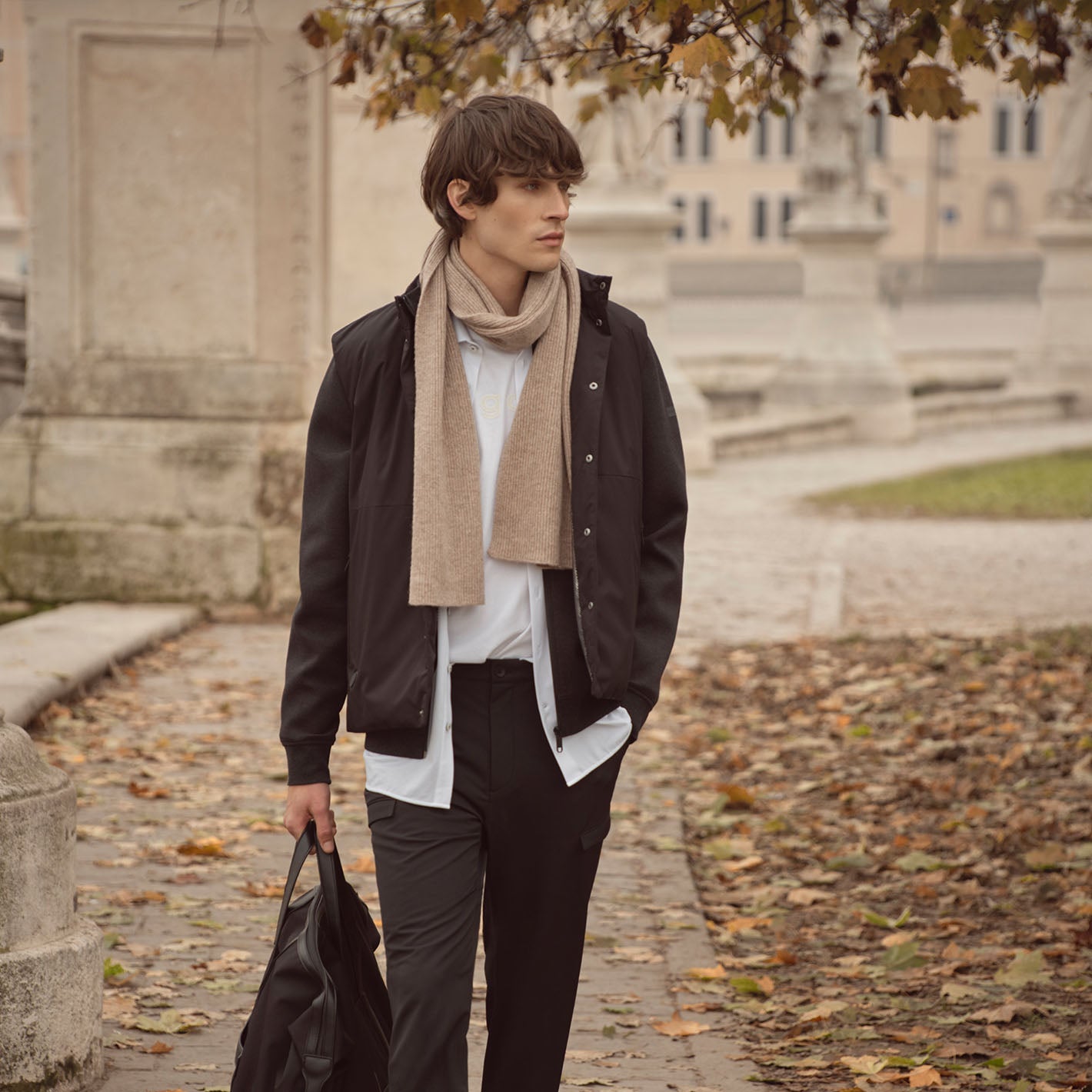 Mann mit Reisetasche in der Hand läuft durch einen herbstlichen Park