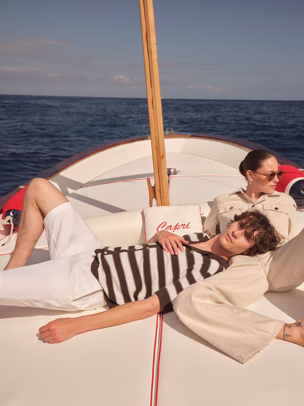 Eine Frau und ein Mann liegen auf einem Boot auf dem Wasser. Der Mann hat den Kopf auf den Bauch der Frau gelegt.