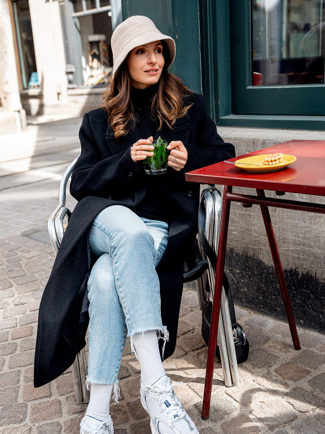 Frau sitzt mit einer Tasse Tee im Kaffee, am Kopf einen LOEVENICH Filzhut