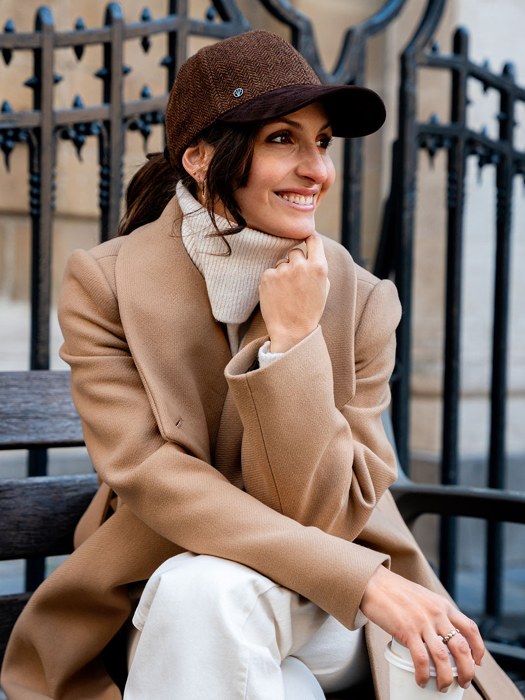 Frau mit LOEVENICH Baseballkappe am Kopf hat den Kopf in die Hand gestützt und lächelt