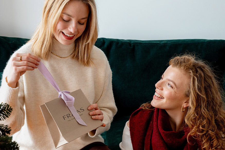 zwei Frauen sitzen am Sofa und öffnen eine FRAAS-Geschenkbox