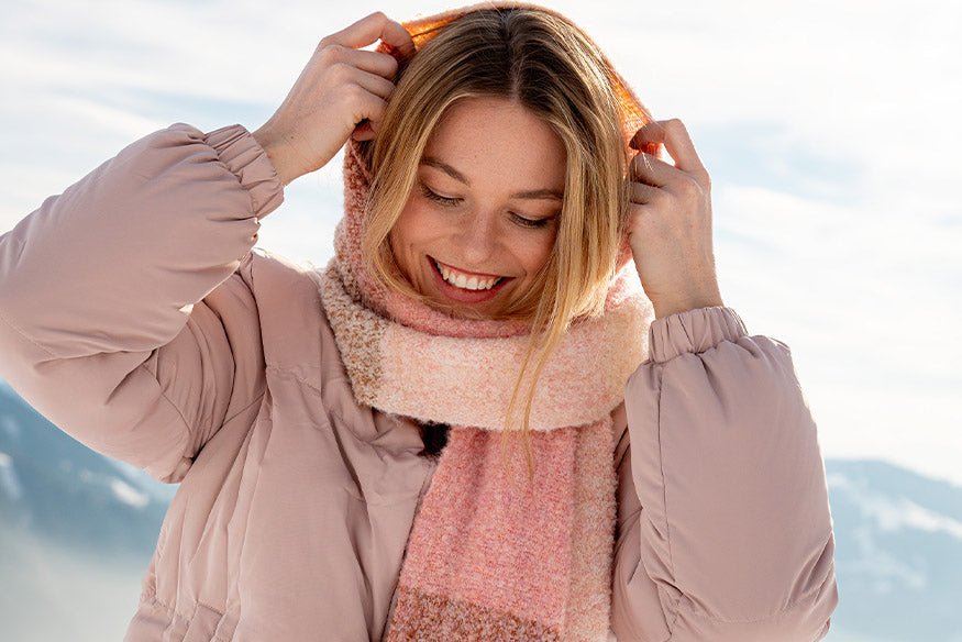 Frau zieht sich ihren Schal wie eine Mütze über die Haare