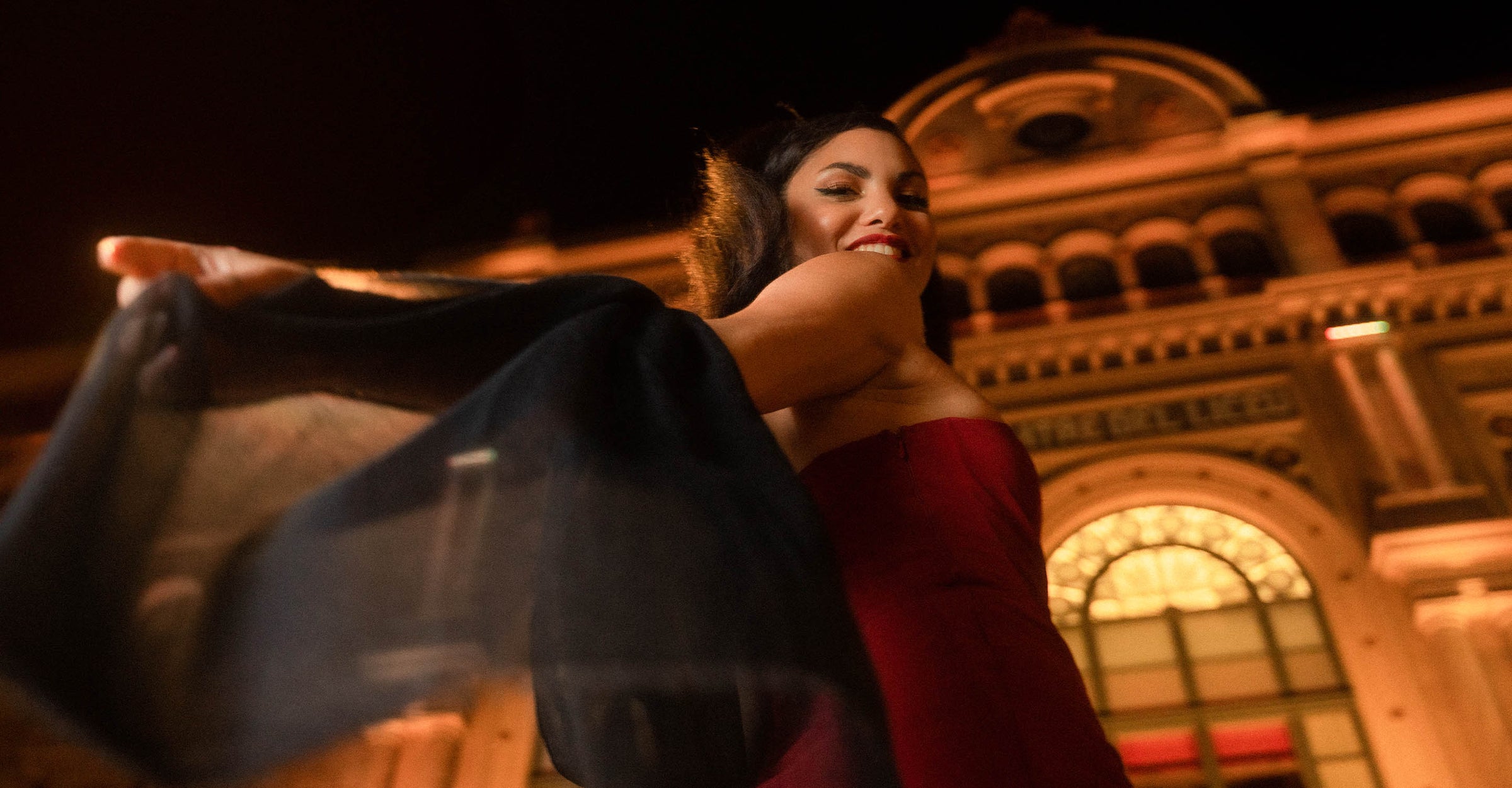 Frau in elegantem Kleid und Stola eilt am Abend in Richtung Theatereingang