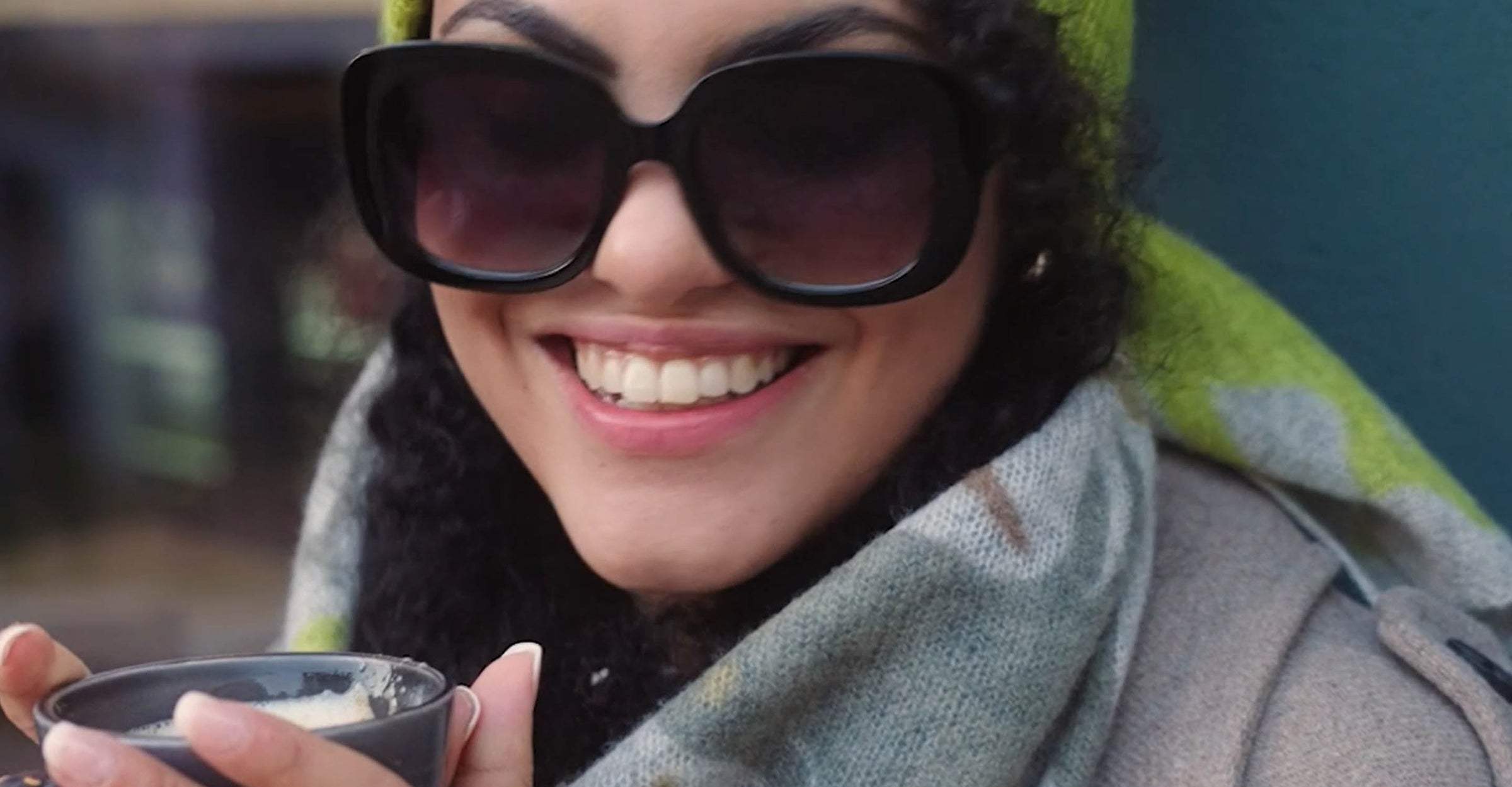 Frau mit Sonnenbrille trinkt einen Kaffee