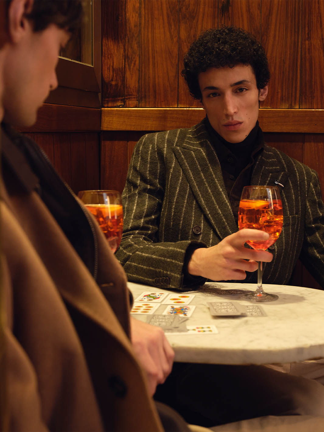 zwei Männer sitzen in einer Bar, trinken etwas und spielen Karten