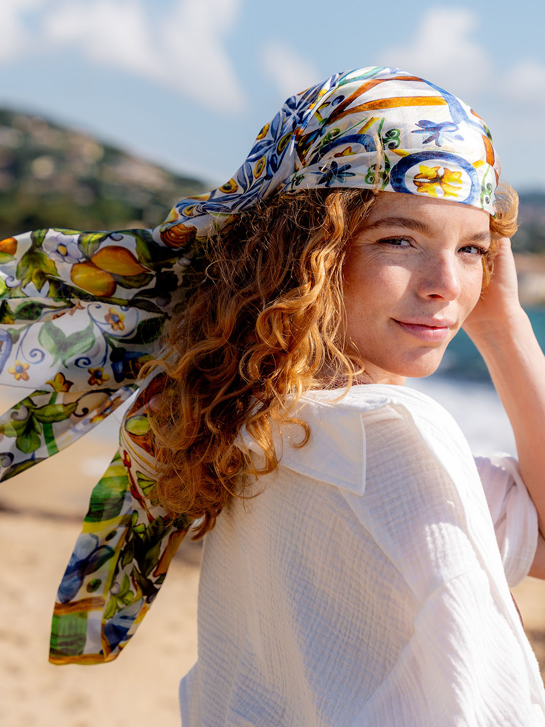 Frau trägt die FRAAS Mosaik-Stola 622010  als Kopftuch und sieht in die Kamera.