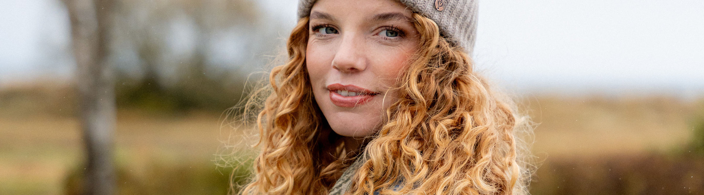 Nahaufnahme einer jungen Frau mit Locken und Strickmütze auf dem Kopf.