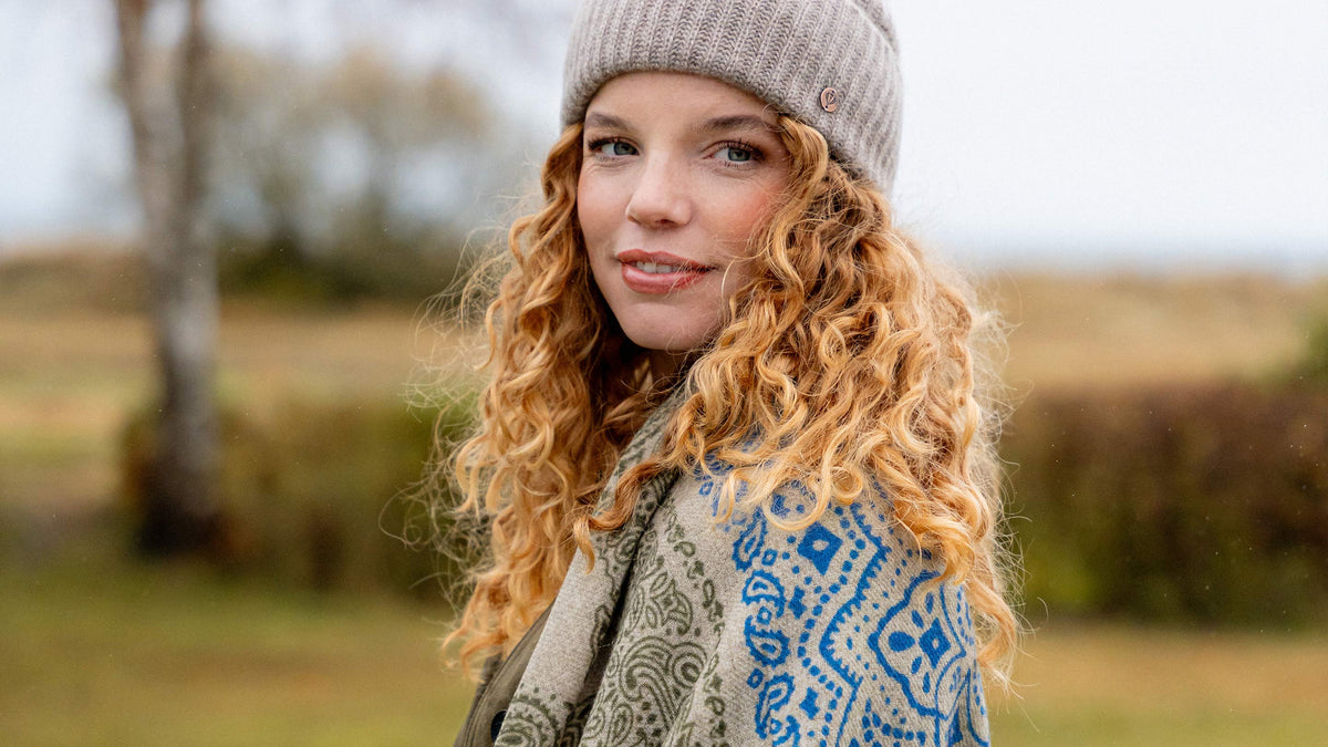 Nahaufnahme einer jungen Frau mit Locken und Strickmütze auf dem Kopf.