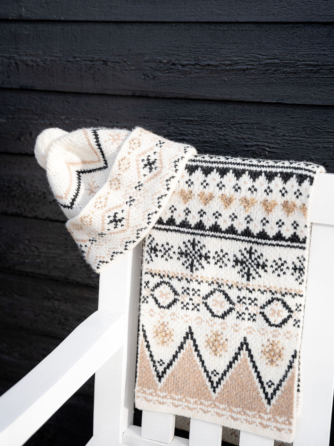 Mütze und Schal mit winterlichem Norweger-Muster hängen über einem Stuhl.