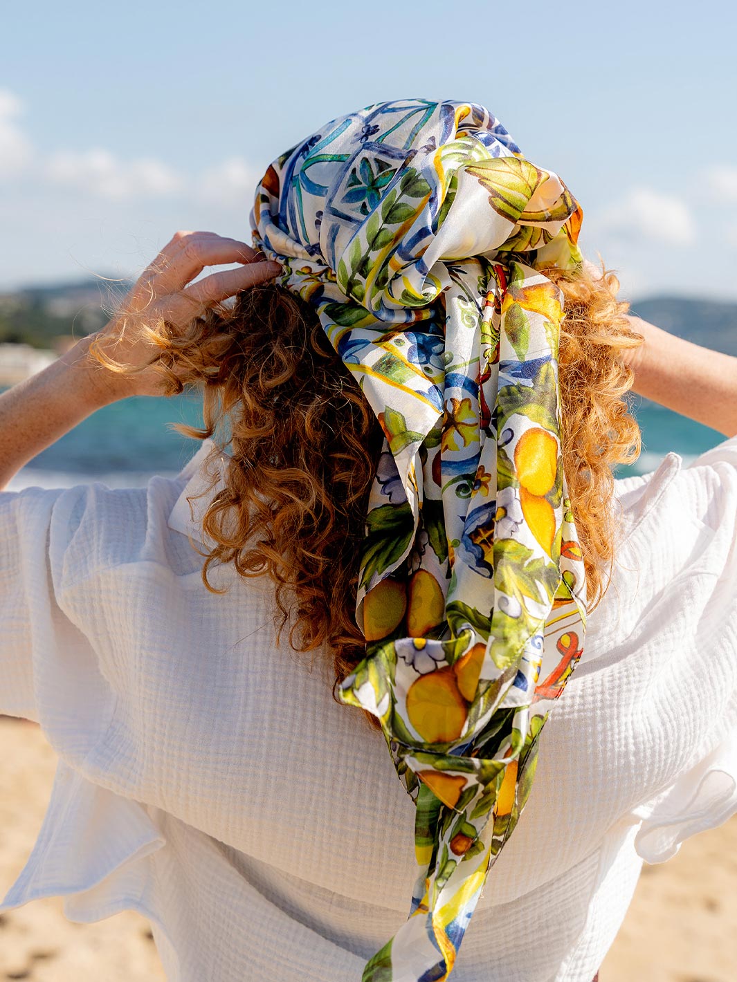 Frau hat sich  die Mosaik-Stola 622010 als Kopftuch umgebunden und steht mit dem Rücken zur Kamera.