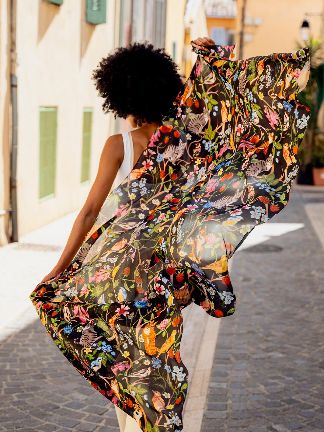 Frau läuft durch die Stadt und lässt die Seiden-Stola 622009 hinter sich im Wind flattern.