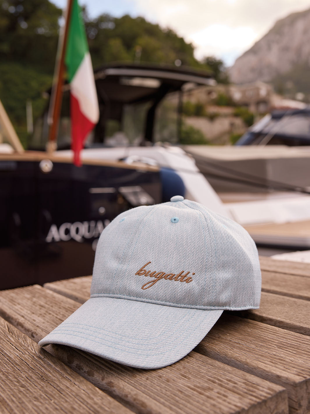bugatti Baseballkappe liegt auf eine Bank, im Hintergrund ist ein Boot zu sehen.