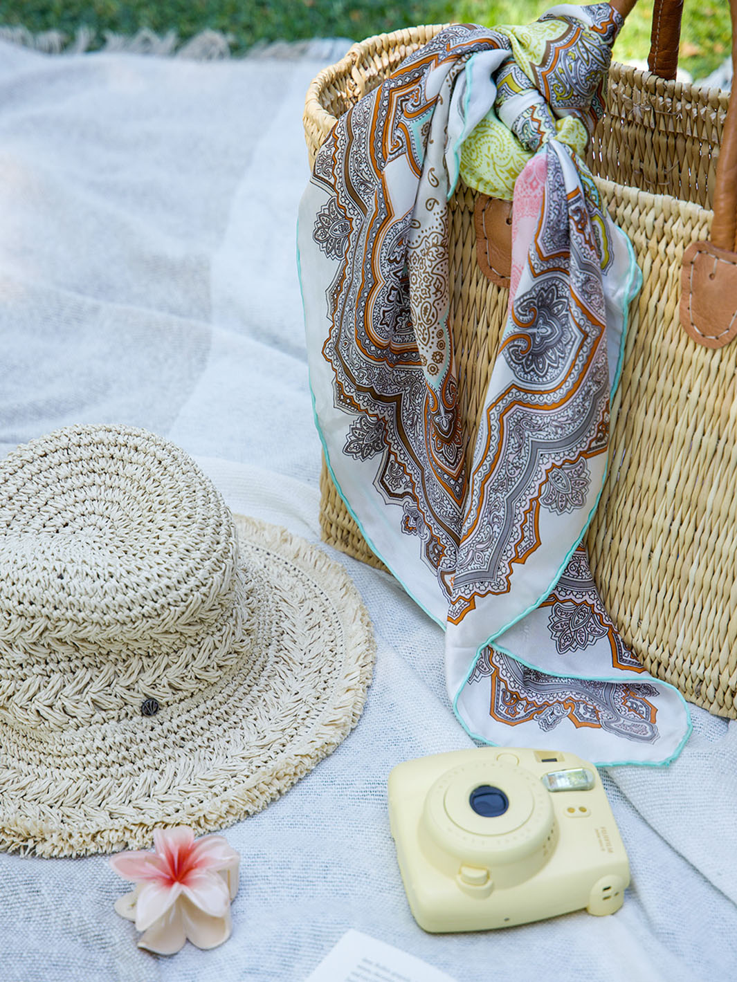 Tasche, Hut und Kamera liegen auf einer Picknickdecke