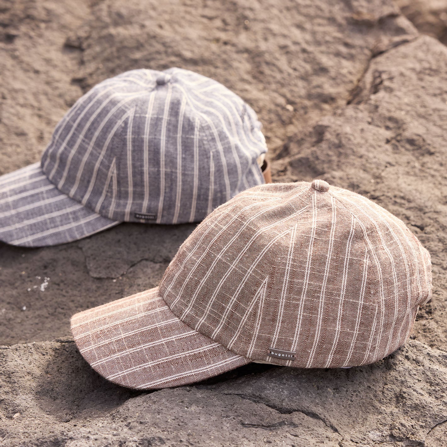 Zwei bugatti Baseballkappen auf einem Stein.