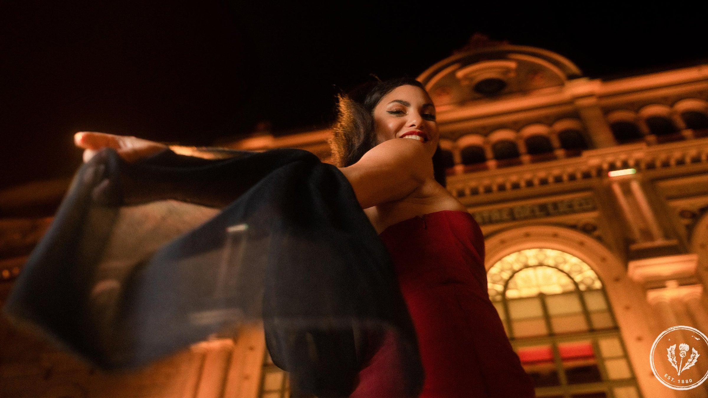 Frau in elegantem Kleid und Stola eilt am Abend in Richtung Theatereingang