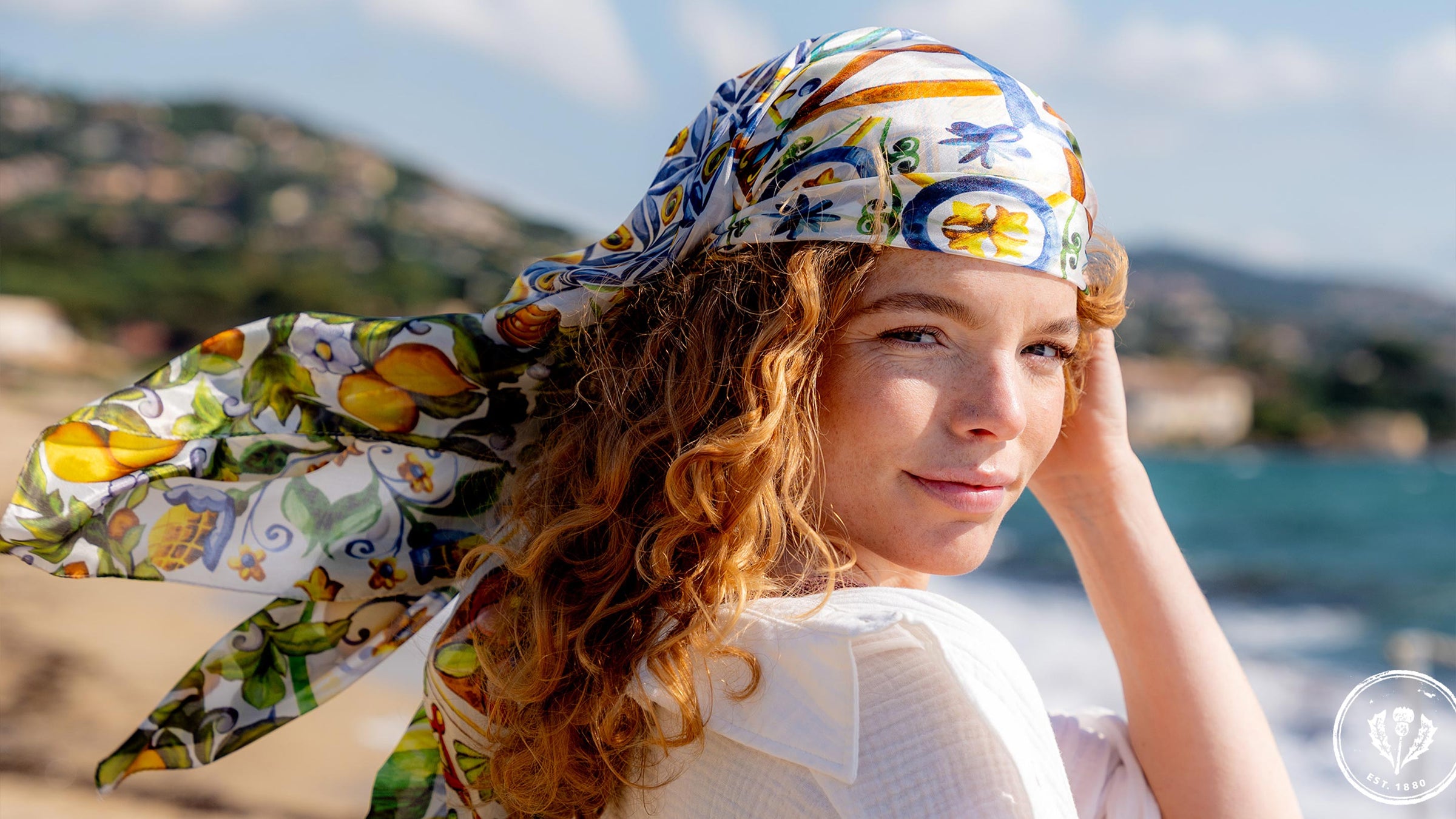 Frau hat sich  die Mosaik-Stola 622010 als Kopftuch umgebunden und blickt in die Kamera.