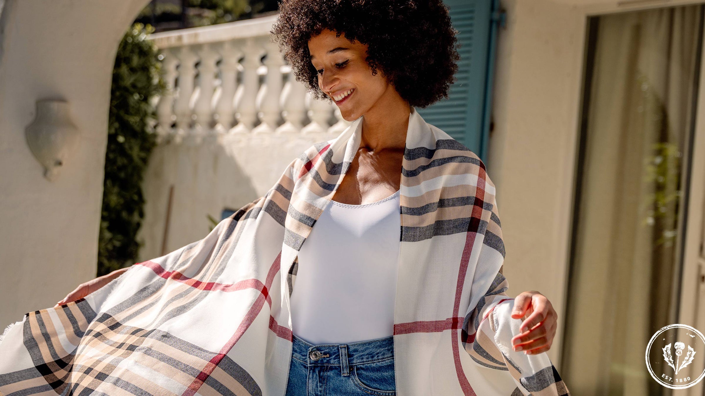 junge Frau hat sich die FRAAS Plaid Stola 631114 um die Schultern gelegt und tanzt auf der Terrasse 