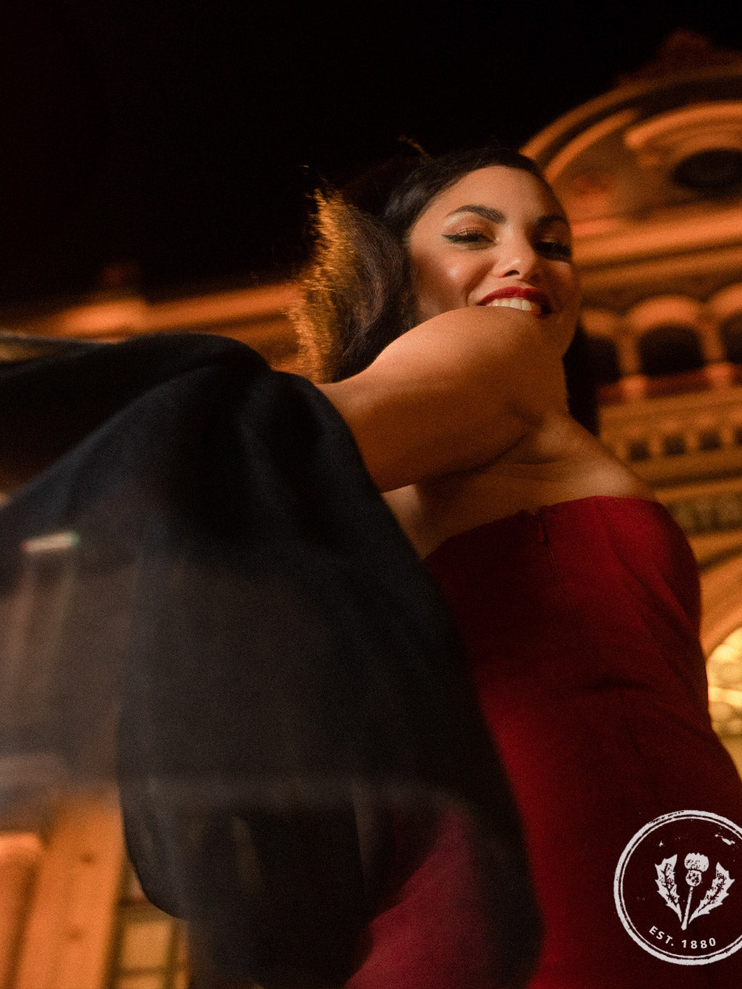 Frau in elegantem Kleid und Stola eilt am Abend in Richtung Theatereingang