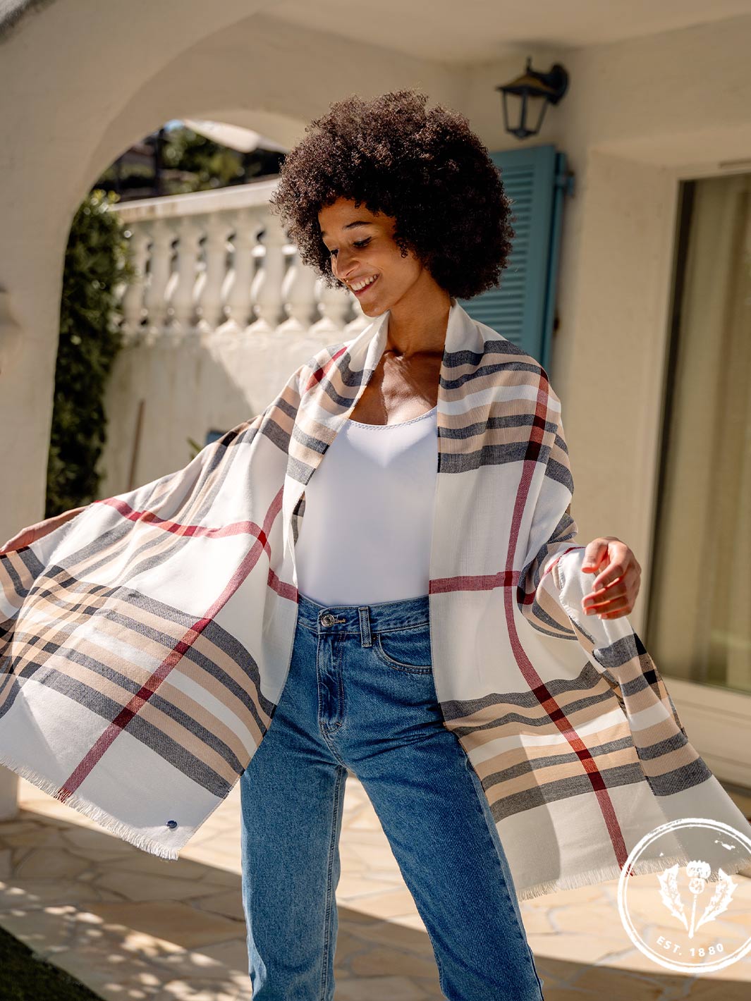 junge Frau hat sich die FRAAS Plaid Stola 631114 um die Schultern gelegt und tanzt auf der Terrasse 