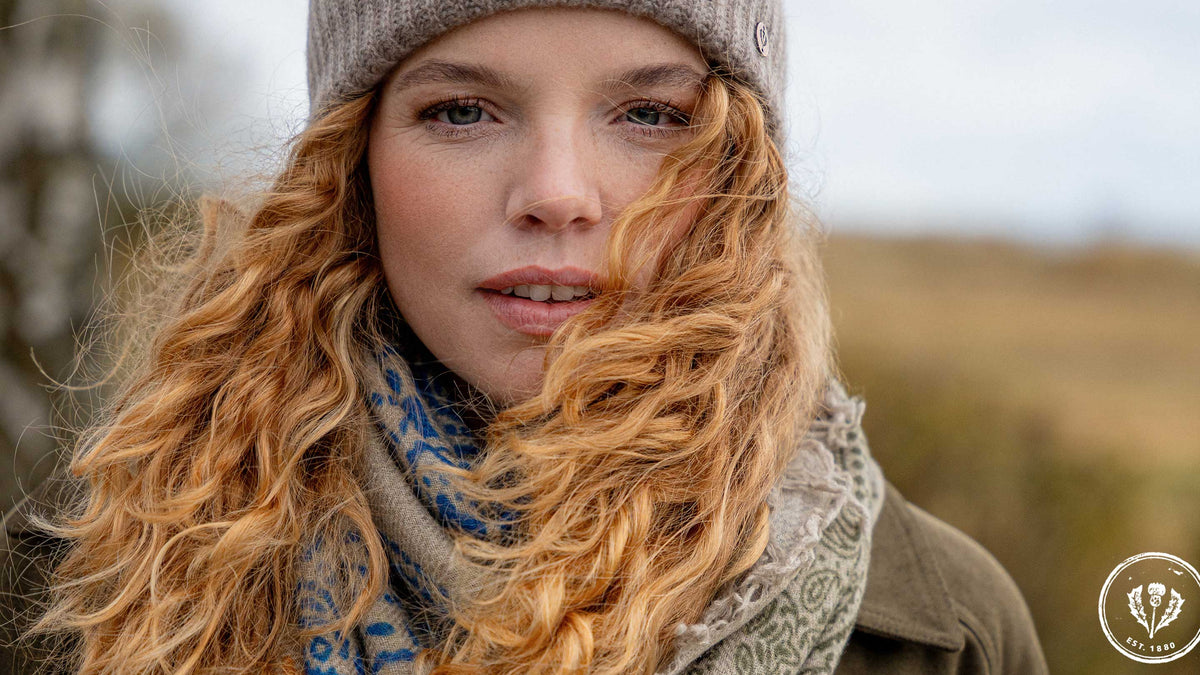 Nahaufnahme einer jungen Frau mit Locken und Strickmütze auf dem Kopf.