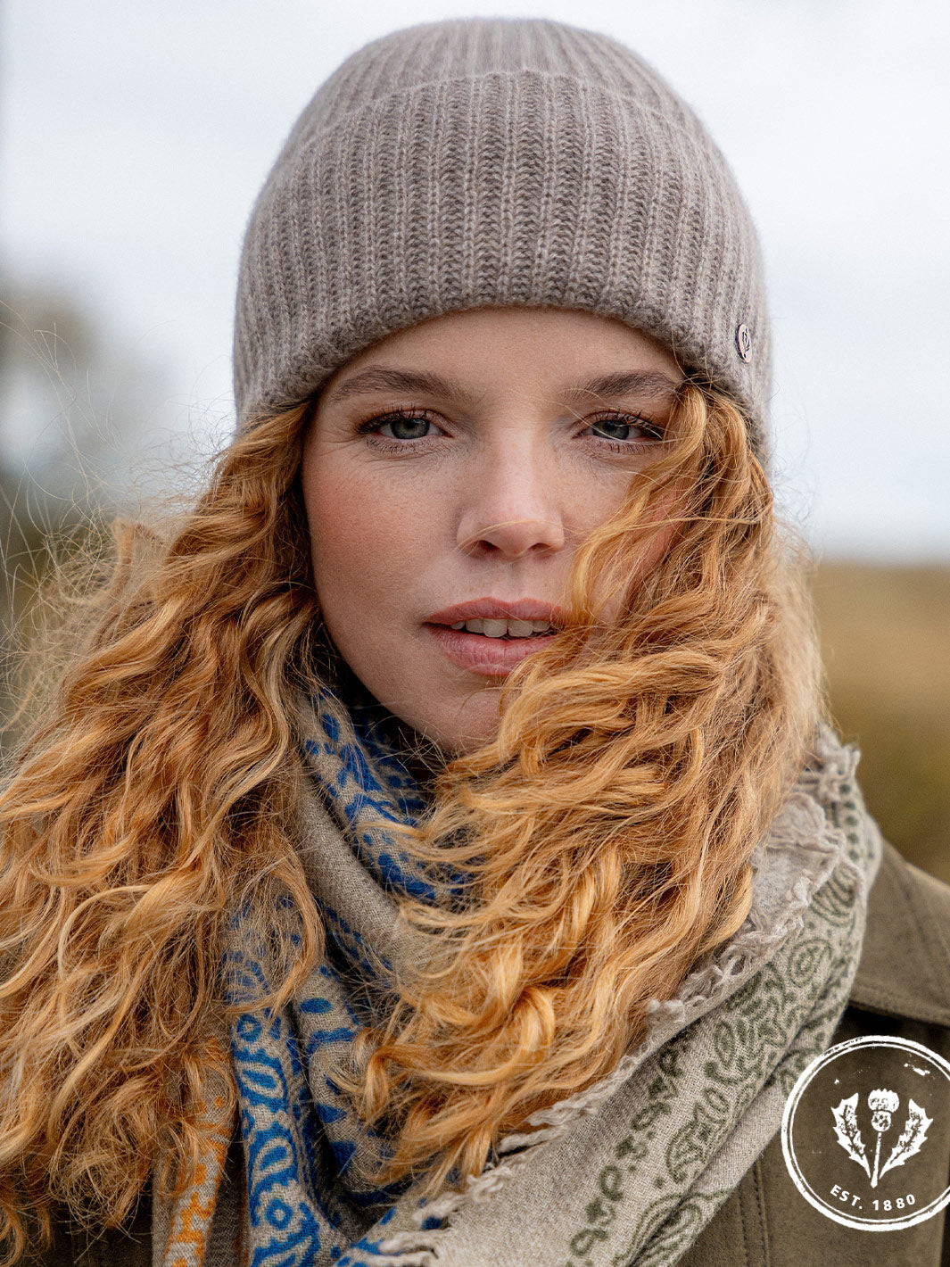 Nahaufnahme einer jungen Frau mit Locken und Strickmütze auf dem Kopf.