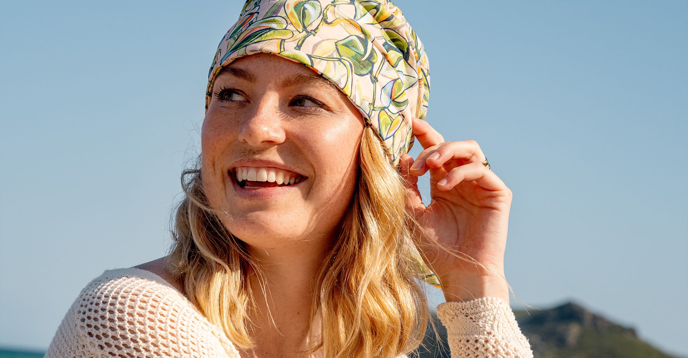 Nahaufnahme einer jungen, lachenden Frau, die die Loevenich Bandana zum Binden mit buntem Blätter-Print 671014 trägt
