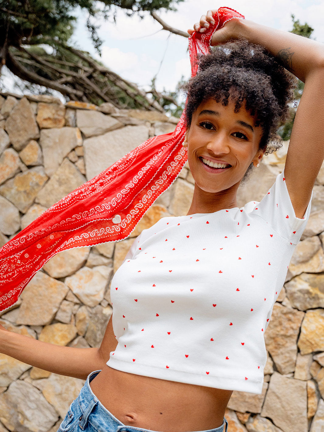  eine Frau steht vor einer Mauer und spielt lächelnd mit dem FRAAS Nickituch 609065